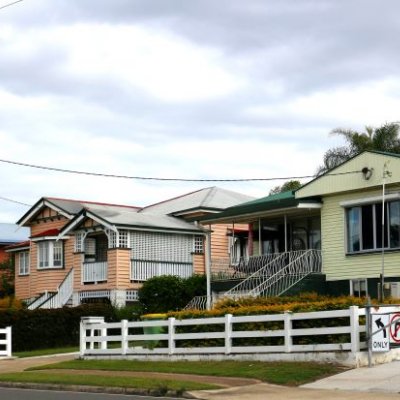 A suburban street with a Queenslander and post-war home.